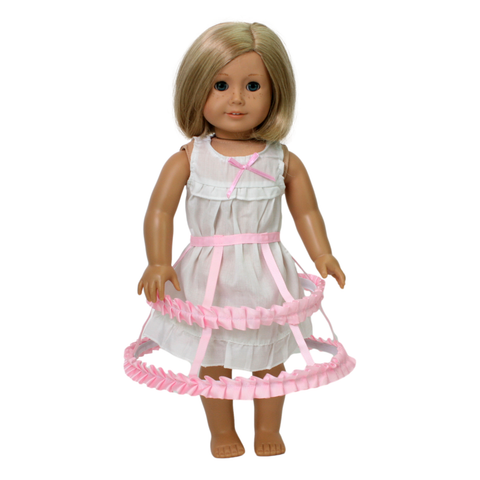 A 18-inch doll wearing a white chemise and a light pink crinoline with a bow detail.