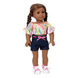 An 18-inch doll wearing a multicolored crop top and denim shorts with a pink ribbon belt.