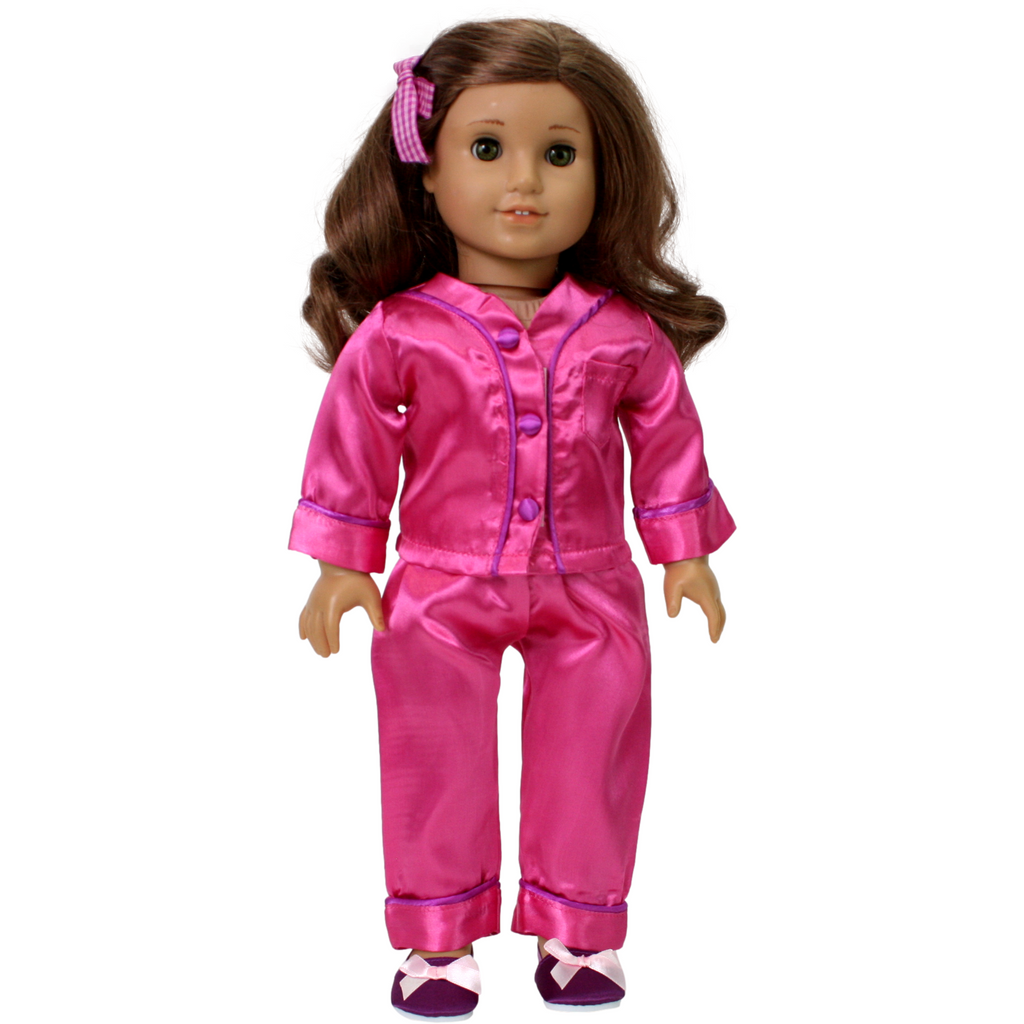 An 18-inch doll wearing a pink satin pajama set with purple trim, including matching slippers and a hair clip.